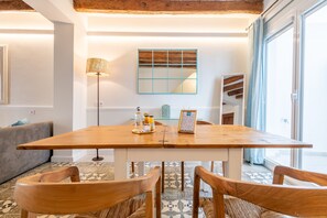 A dining area with a wooden table, chairs, a lamp, a mirror, and a view of the outdoors. - Apartment 'Can 32 1 Habitación' with Private Terrace, Wi-Fi and Air Conditioning (Pollença)