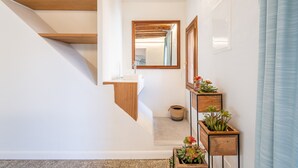 A staircase with wooden beams, a white wall, a mirror, and potted plants.