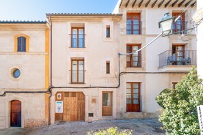 Un edificio con diverse finestre, una porta in legno e un balcone con una sedia.