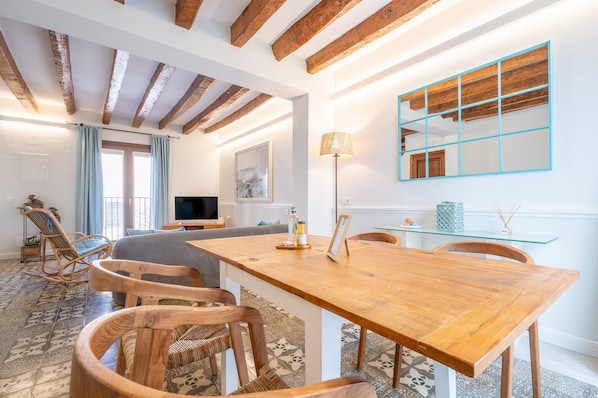 Un vaste espace de vie comprenant une table à manger en bois, des chaises, un canapé et un téléviseur.