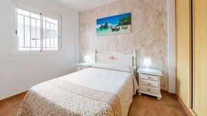 A bedroom with a bed, nightstands, a painting, and a wardrobe.