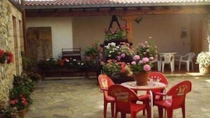 Um pátio com piso de pedra, uma mesa redonda com cadeiras e plantas em vasos.