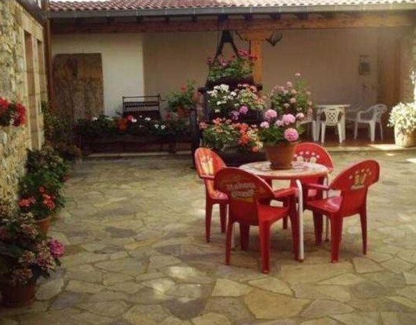 A patio with stone flooring, a round table with chairs, and potted plants.