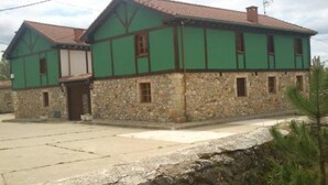 Um edifício de dois andares com base de pedra e paredes superiores verdes, com telhado em telhas e uma pequena varanda.