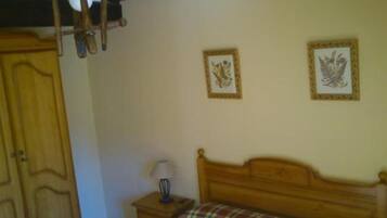 Un dormitorio con una cama de madera, una mesita de noche con una lámpara y dos cuadros enmarcados en la pared.