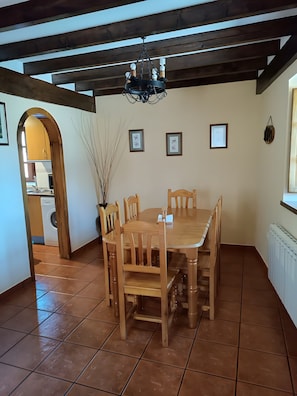 A dining area with a wooden table and chairs, a chandelier, and framed pictures on the wall.