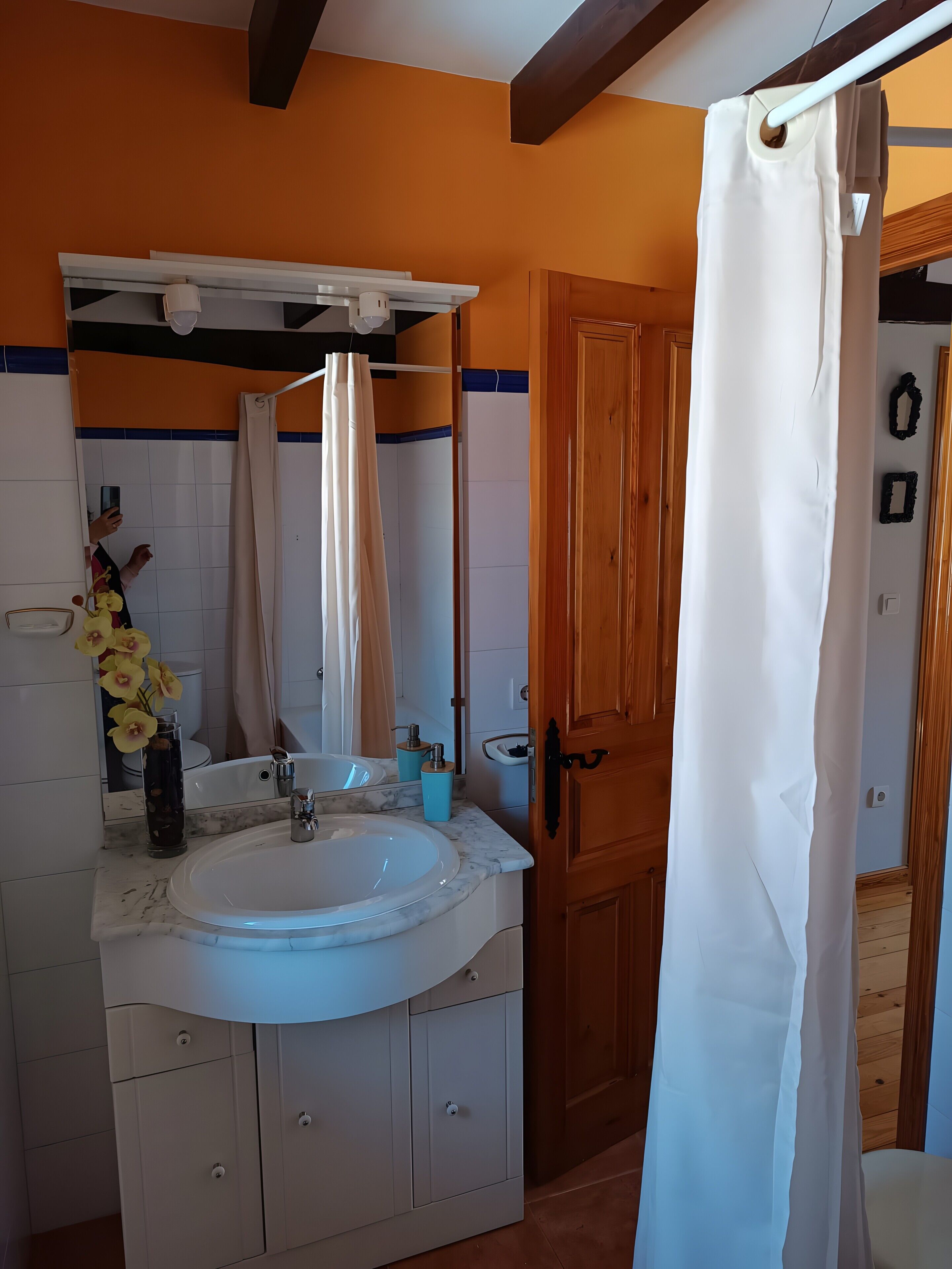 Ein Badezimmer mit Waschbecken, Spiegel und Holztür.