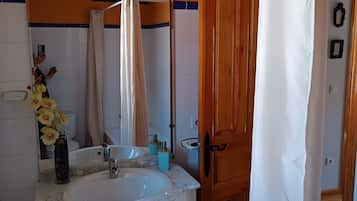 Ein Badezimmer mit Waschbecken, Spiegel und Holztür.