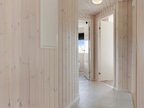 Ein Korridor mit Holzvertäfelung und Fliesenboden, der zu einem Raum mit einer Tür führt.