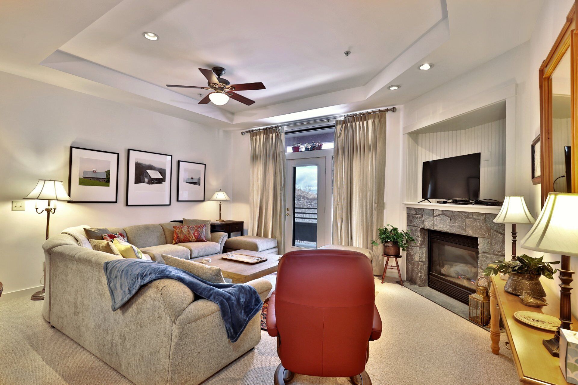 Una sala de estar moderna con un sofá, sillones, una chimenea, un televisor y cuadros enmarcados en la pared.