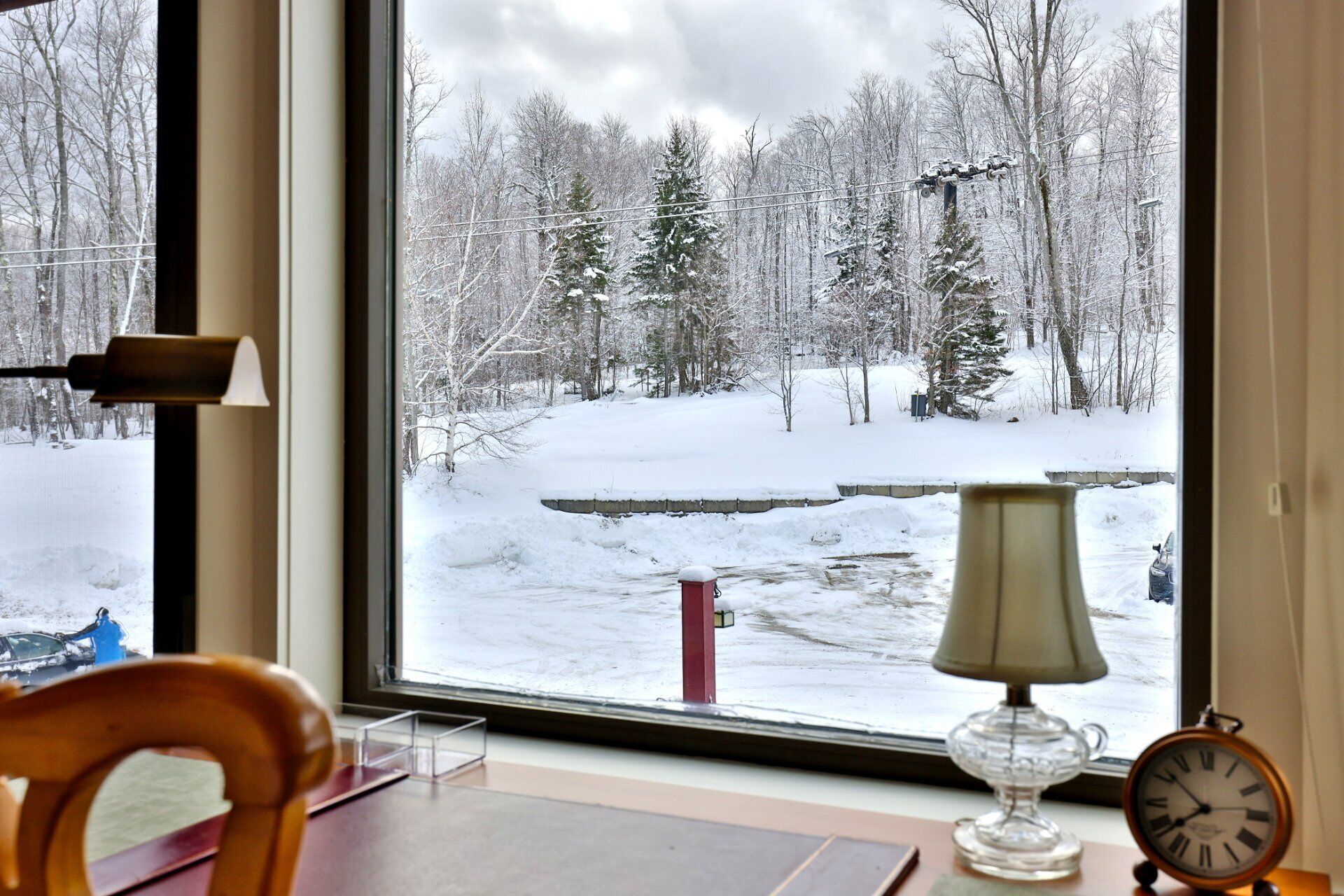 A room with a large window overlooking a snowy landscape with trees and a road.