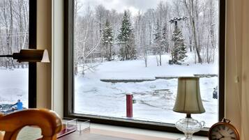 A room with a large window overlooking a snowy landscape with trees and a road.