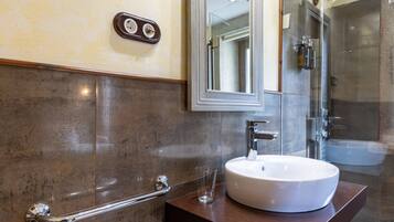 A bathroom with a white sink, a glass shower enclosure, and a handrail.