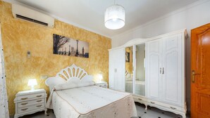 Un dormitorio con cama, mesitas de noche, un armario y un cuadro en la pared.