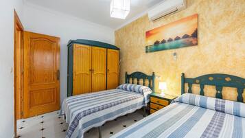 Un dormitorio con dos camas, un armario de madera y un cuadro en la pared.
