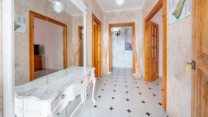Un pasillo con un tocador de mármol, puertas de madera y piso de baldosas.
