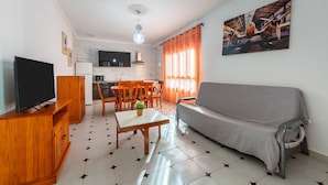 Una sala de estar con sofá, televisor, muebles de madera y un comedor con sillas y una mesa.