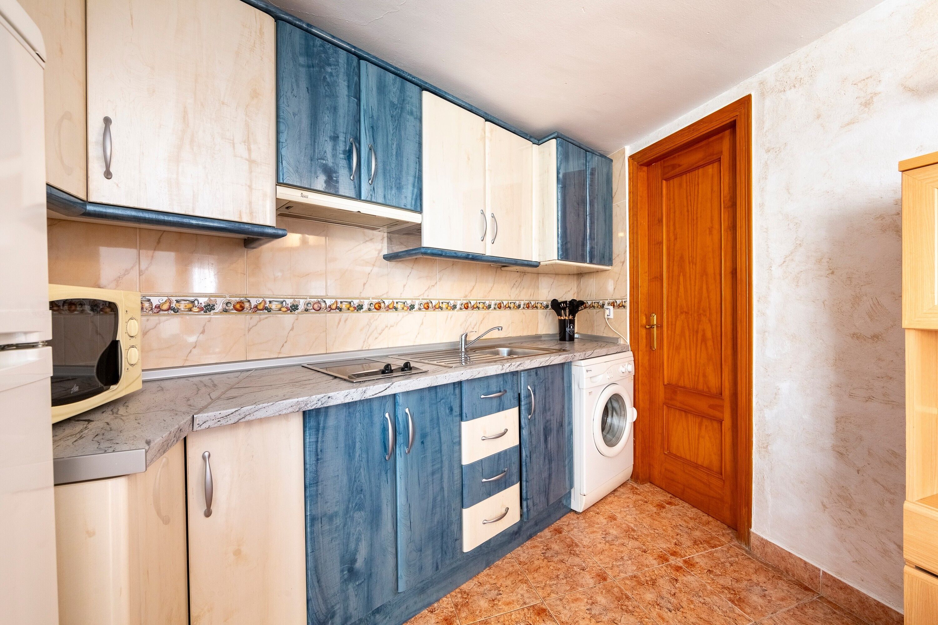 A compact kitchen with a washing machine, a microwave, and a sink.