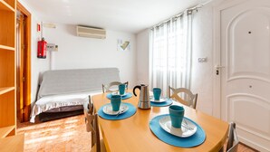 A room with a bed, a table set with blue cups and a silver pitcher, a fire extinguisher, and a white door. - Apartment 'La Noria 3' with Air Conditioning (Pozo de los frailes)