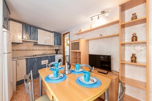 Una cocina moderna con comedor, televisor y estantes con frascos.