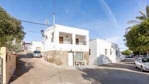 A white building with a stone facade, a balcony, and a door with a window. - Apartment 'La Noria 3' with Air Conditioning (Pozo de los frailes)