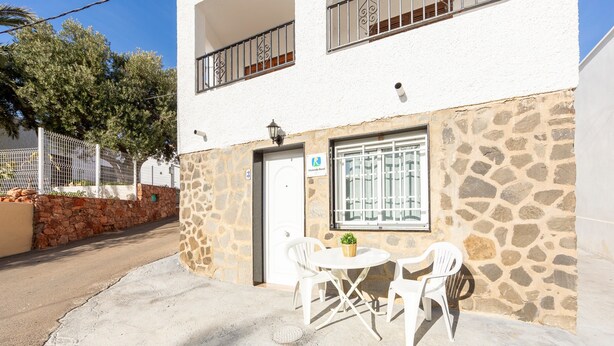 A two-story building with a stone facade, a door with a window, and a small table with chairs outside. - Apartment 'La Noria 3' with Air Conditioning (Pozo de los frailes)
