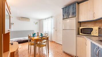 Cocina compacta con mesa, sillas, microondas y refrigerador.