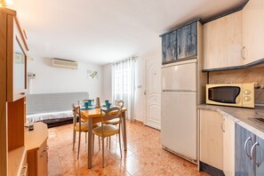 Cocina compacta con mesa, sillas, microondas y refrigerador.
