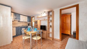 A compact kitchen with a dining area, a television, and a wooden cabinet. - Apartment 'La Noria 3' with Air Conditioning (Pozo de los frailes)