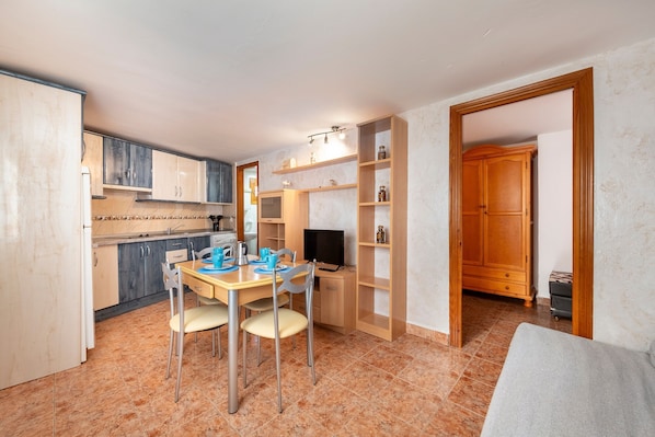 Una cocina compacta con comedor, televisor y un mueble de madera.