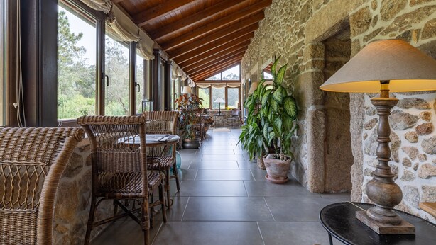 A covered outdoor seating area with wicker furniture, stone walls, and potted plants. - Bed and Breakfast 'Alca' with Private Garden and Wi-Fi (Camariñas)