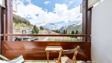 Eine Holzterrasse mit einer Bank und einem Tisch, mit Blick auf eine Berglandschaft mit einer Straße und einer Brücke.