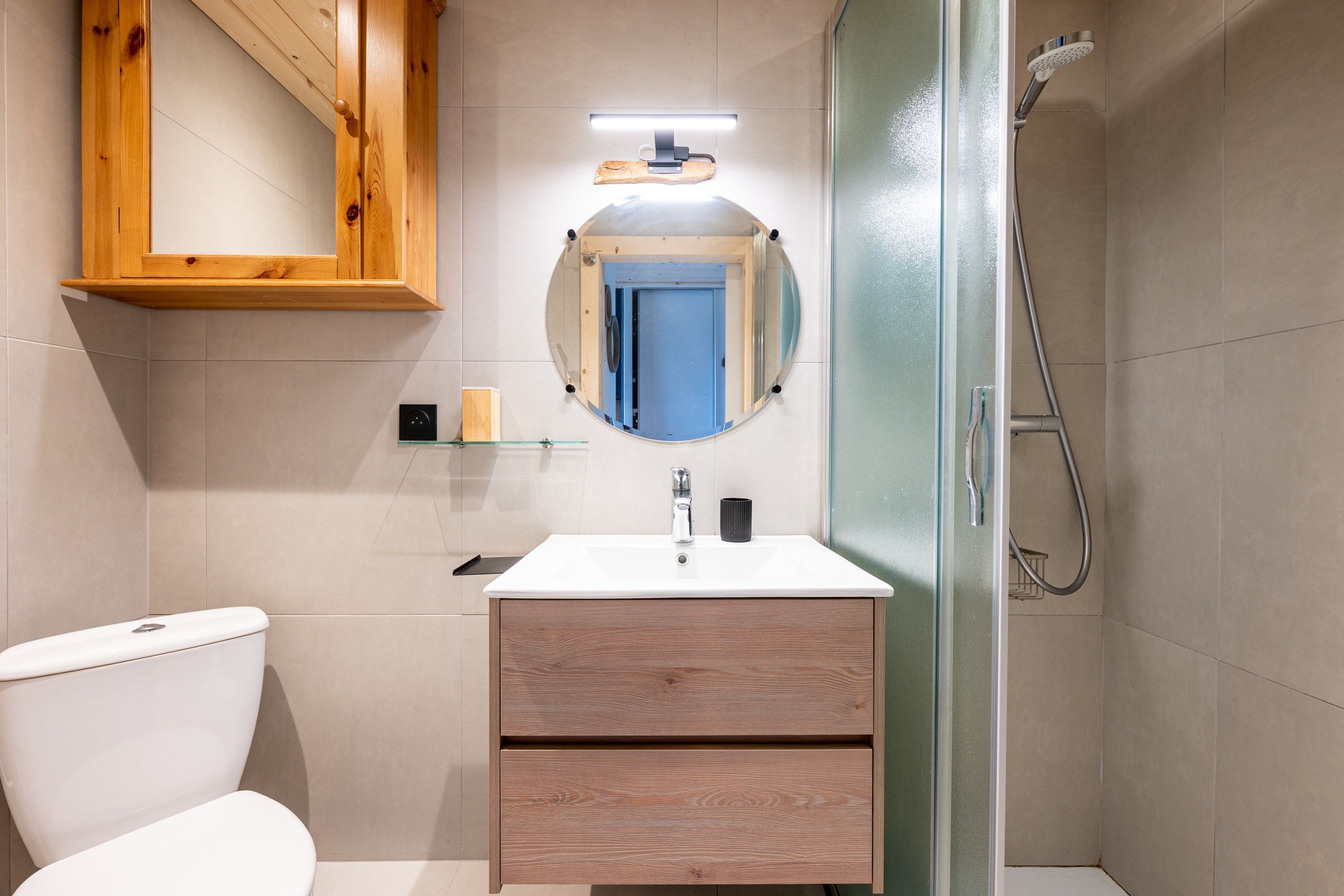 Een badkamer met toilet, wastafel met spiegel en douche.