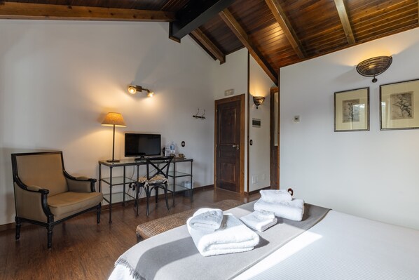 A hotel room with a bed, a desk with a computer, a chair, and a television.