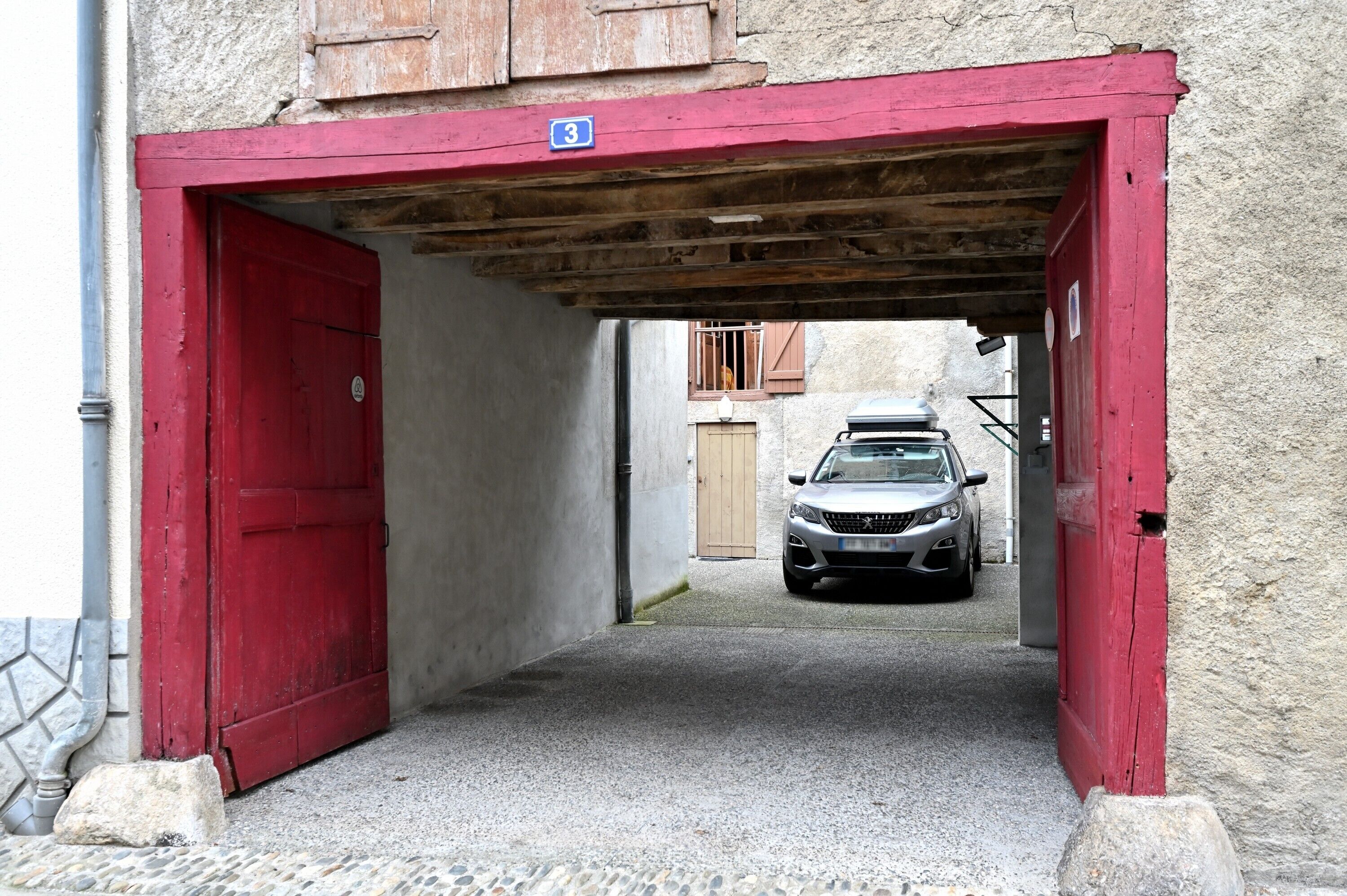 A narrow alleyway with a red door and a car parked inside.