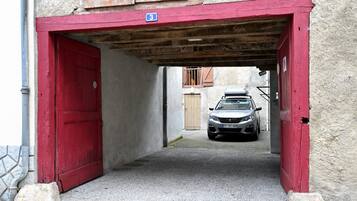 A narrow alleyway with a red door and a car parked inside.