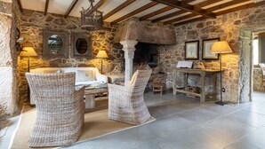 Una habitación de paredes de piedra con chimenea, sillas de mimbre, un sofá y una mesa.