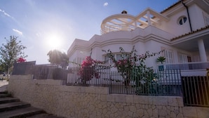 A modern house with a stone wall, a metal fence, and a circular architectural feature.