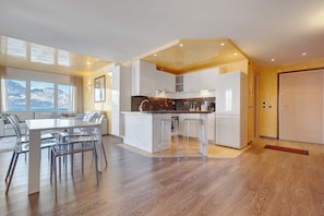Une cuisine moderne dotée d’un îlot central, de meubles blancs et d’un coin repas avec une table et des chaises.