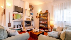 Ein Wohnzimmer mit Kamin, Bücherregalen, einem Fernseher und einem Sofa.