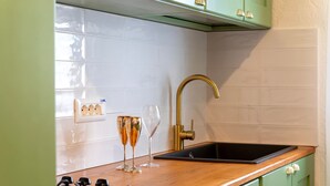 Eine Küche mit einer Holzarbeitsplatte, einem schwarzen Spülbecken, einem Gasherd und grünen Schränken.