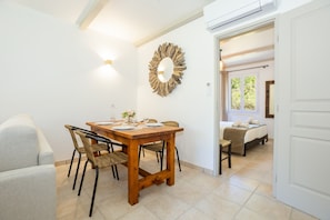 A dining area with a wooden table, four chairs, a mirror, and a sofa.