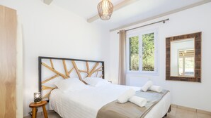 Ein Schlafzimmer mit Bett, Nachttisch, Fenster und Spiegel.