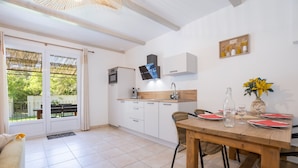 Una cocina moderna con comedor, horno empotrado y un amplio ventanal con vistas al verdor.