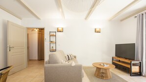 Un soggiorno moderno con un divano, una TV, un tavolino in legno e una lampada a sospensione.