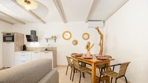 Una cucina moderna con elettrodomestici integrati, un'area pranzo con tavolo e sedie in legno e una ventola a soffitto.
