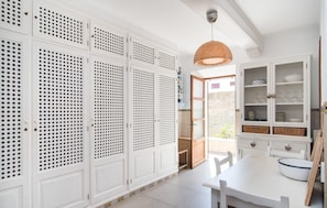 Une pièce avec des meubles de rangement blancs, une table à manger et un luminaire suspendu.