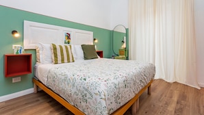 A bedroom with a bed, a headboard, a nightstand, a mirror, and a window with curtains. - Room 'Angelica' with Wi-Fi and Air Conditioning (Catania)