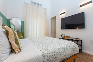 A bedroom with a bed, a television mounted on the wall, a mirror, and a bedside table with a lamp. - Room 'Angelica' with Wi-Fi and Air Conditioning (Catania)