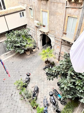 Un patio con plantas en macetas, una motocicleta y un edificio con balcón.